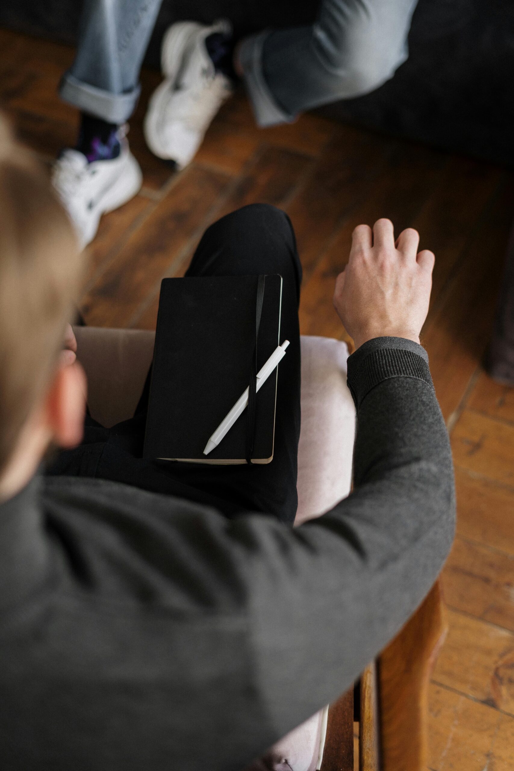 Overhead view of two people in a consultation, one with a notebook and pen.